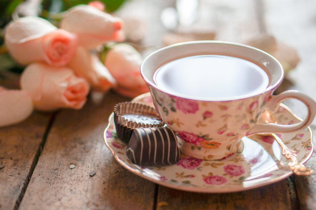 Tea cup with tea and chocolate on the side.